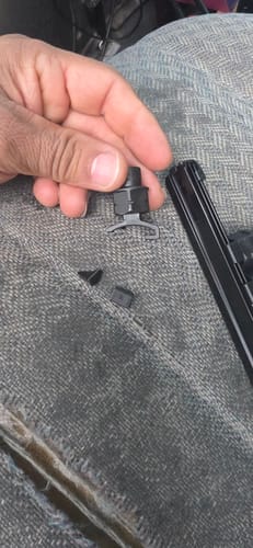 Customer's hand holding a socket with the broken black plastic holder clip pieces shown on a gray seat.