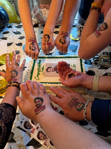Customers showing off their Grad! temporary tattoos on their hands and arms during a graduation party.