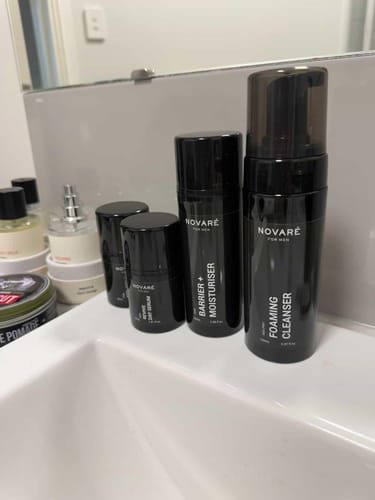 Customer's CORE FOUR HYDRATE BUNDLE of black skincare bottles arranged on a bathroom sink.