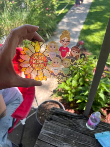 Customer holding a personalized sunflower suncatcher with "Best Mom Ever" and five illustrated people.