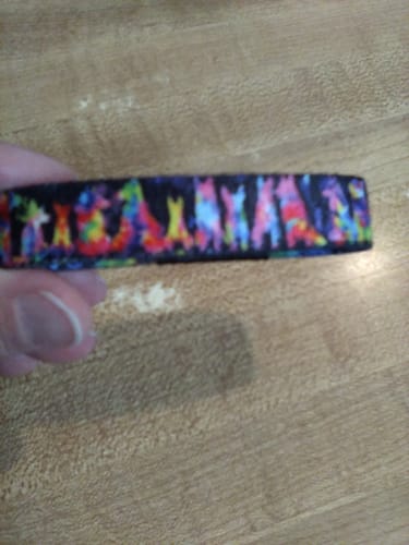 Close-up of a reviewer holding the Love Stays Bracelet, showing the colorful pattern of dog silhouettes.