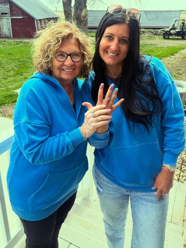 Customer and another person in matching blue sweatshirts, smiling while showing their Navae Birthstone Rings.
