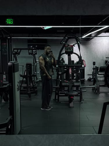 Reviewer taking a mirror selfie in a gym wearing the dark, baggy Core Baggy Sweats.