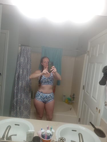 Reviewer taking a mirror selfie in a bathroom, wearing the floral high-waist bikini set.