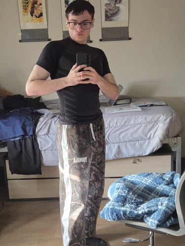 Customer taking a mirror selfie to show the fit of the black Gothic Compression Tee.