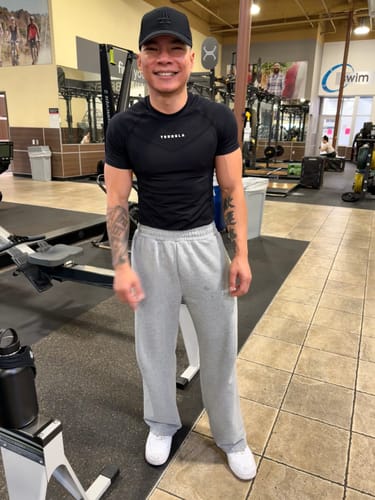 Reviewer at a gym showing the relaxed fit of the grey Classic Baggy Sweats.