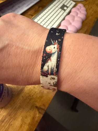 Customer wearing the Whimsy Bracelet, showing the detailed, whimsical unicorn design against a dark background.