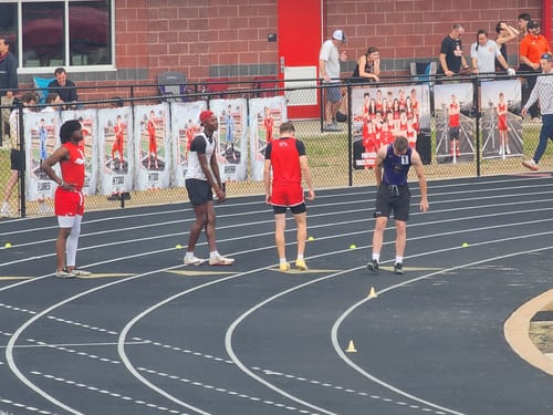 A customer's view of a runner in black 'Break Your Chains' performance shorts at a track meet.
