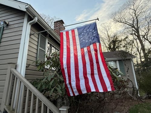 Customer's 1776 to 2026 Betsy Ross Flag flying from a flagpole attached to the side of a house.