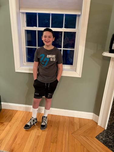 Customer smiling while wearing the black 'Cross' Youth Performance Shorts indoors.