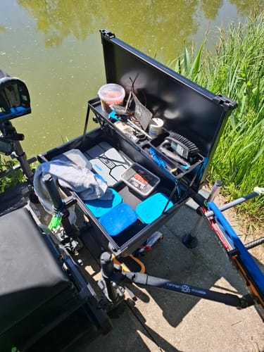 Recensent's PRO FEEDER TRAY open en gevuld met aas en visgerei, opgesteld aan de waterkant.