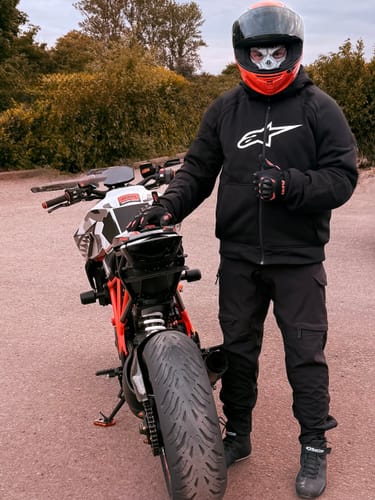 Reviewer in full gear standing next to their KTM Superduke 1290, showing the modified rear end of the bike.