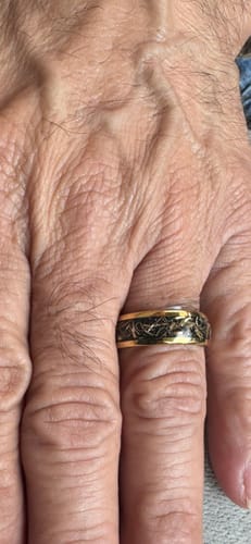 Close-up of a customer's hand wearing the Caldris ring, which has a gold band and black inlay.