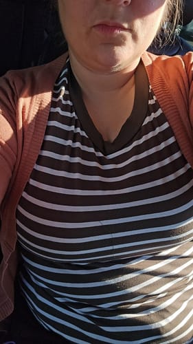 Close-up of a reviewer wearing the brown and white Tried & True Striped Tee layered under a cardigan.