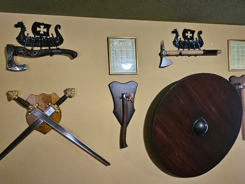 Customer's two black Drakkar Axe Holders displaying a bearded axe and a battle axe on a wall collection.
