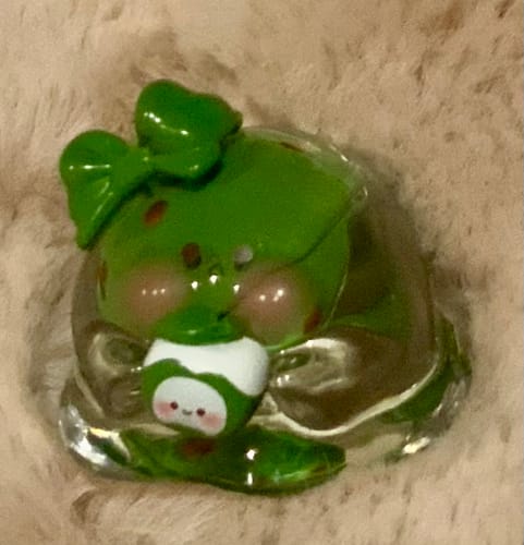 Customer's shiny green Bubble Eggs Winter Series figure with a bow, holding a small character on a fluffy surface.