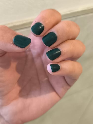 Kundin zeigt ihre kurzen Nägel, die mit den tiefgrünen UV-Gelfolien Evergreen Dream lackiert sind.