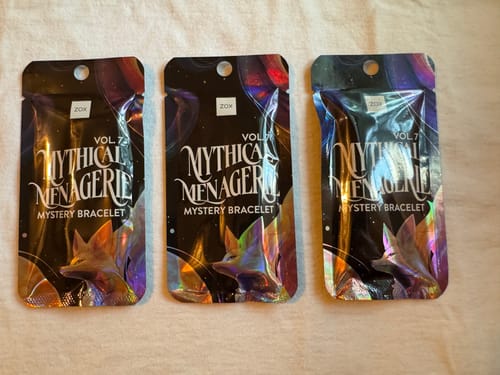 Customer shows three sealed 'Mythical Menagerie' mystery bracelet packs from their Mystery Club+ shipment.