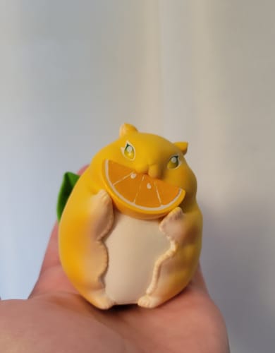 Customer holding a yellow Fruit Fairy hamster figurine with an orange slice in their hand.