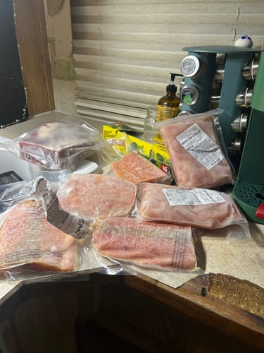 Customer shows the various frozen, vacuum-sealed cuts from the Beef Steak Gift Box spread out on a kitchen counter.