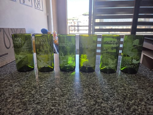 Cliente muestra el juego de 6 vasos verdes Arquitectura Lover alineados sobre una encimera.