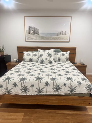 Customer's 'Path to the Sea' panoramic art print in a wood frame, hung above a bed in a bedroom.