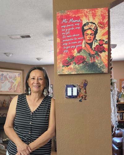A customer's mother smiling next to the Mi Mamá Poetry Canvas Print mounted on a wall.