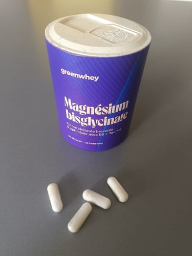 Client montrant le pot violet de Magnésium Bisglycinate et quatre gélules blanches.