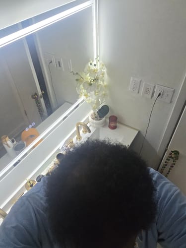 Overhead view of a reviewer's thick, curly hair, showing some thinning on the crown in a review for Rennora Hair Growth Serum.