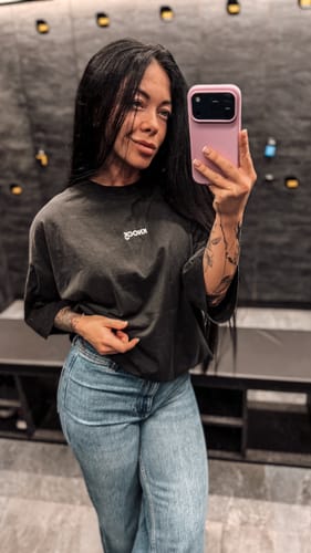 Customer taking a mirror selfie wearing the dark, oversized VINCIT QUI PATITUR VINTAGE TEE.