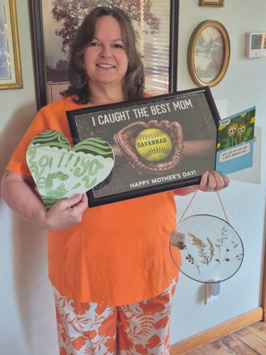 Customer smiling and holding her framed 'We Caught The Best Mom' personalized poster.