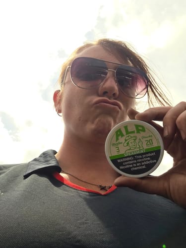 Reviewer making a face while holding up a tin of ALP Spearmint pouches, for which the Leather Holster is designed.