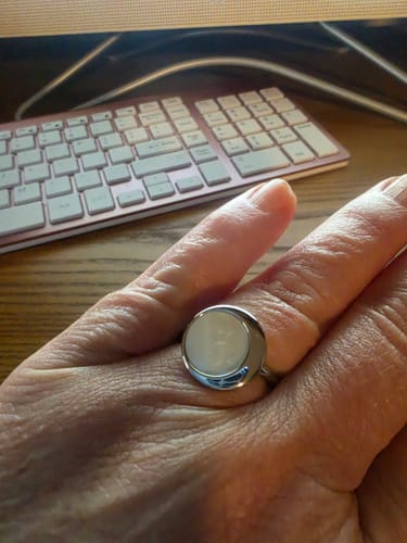 Customer's hand wearing the Moonlight Mother of Pearl Ring, showing its substantial size and shiny band.