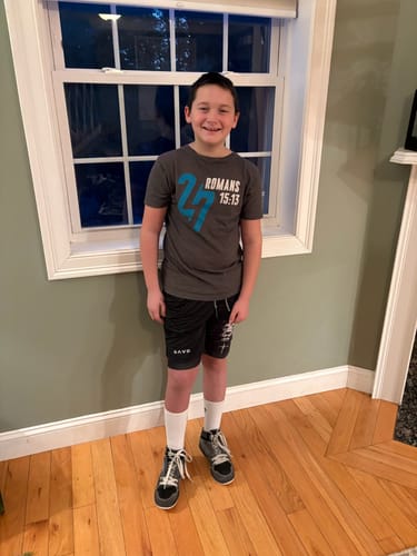 A customer's grandson smiling while wearing the white Youth & Women’s Christian Performance Socks indoors.