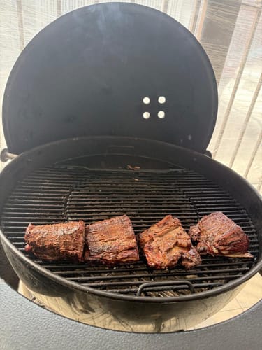 Reseñador mostrando cuatro tablitas de lomo cocinadas en un asador.