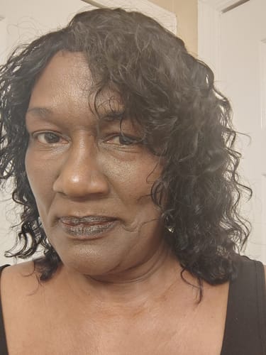 Close-up of a reviewer wearing the curly, dark HAUTY human hair wig indoors.