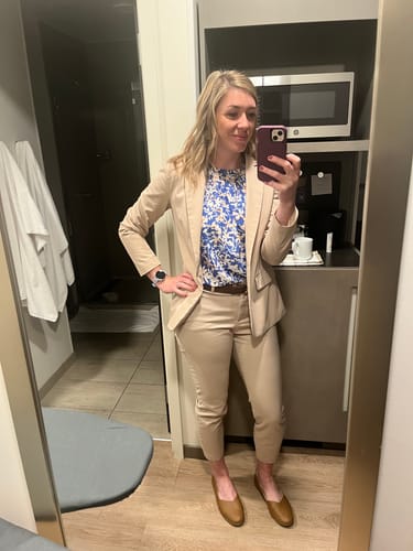 Reviewer wears the floral Blossoming Smocked Top Blouse layered under a tan blazer with matching pants.