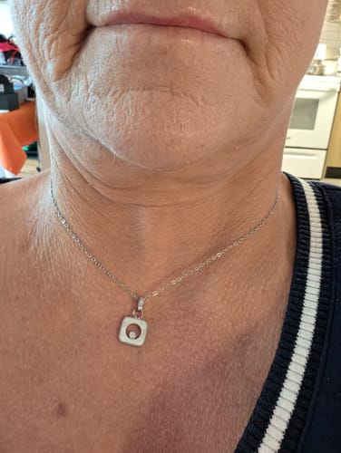 Close-up of a reviewer wearing the silver-toned Square Mother of Pearl Pendant to show its small size.