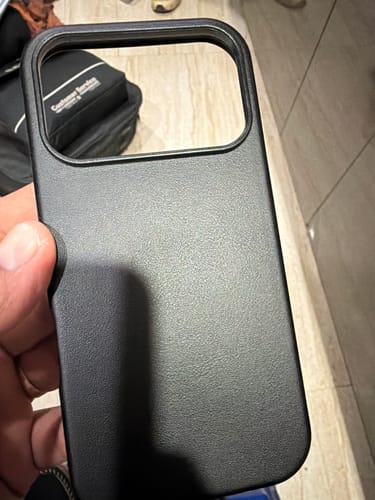 Customer's hand holding the textured, royal black Signature Leather Magsafe Case.