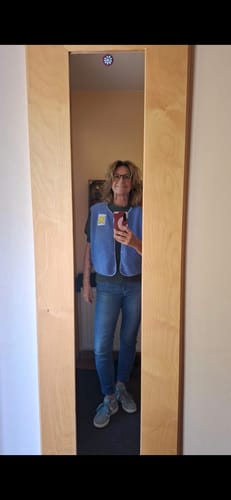 Kundin macht ein Spiegelselfie und trägt die blaue Teddy Weste SMILEY PATCH 2.0 zu Jeans.