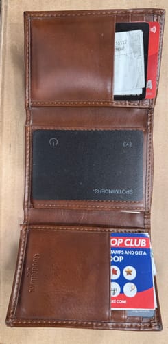 Customer's black SPOTMINDERS Tracking Card shown inside an open brown leather wallet.