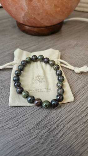 Avis d'un client sur le bracelet Jaspe Sang de Dragon, posé sur sa pochette sur une table en bois.