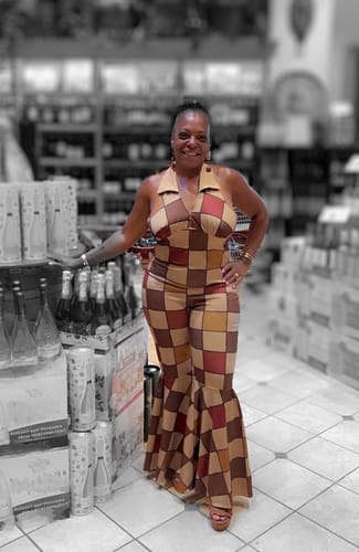 Reviewer poses indoors wearing the 1970s geometric pattern jumpsuit, showing off the halter neck and wide bell-bottom legs.
