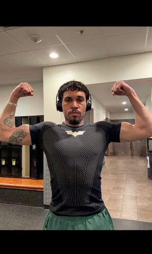 Reviewer flexing in a gym while wearing the fitted black Batman Compression Tee.