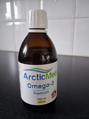Kundens flaska med ArcticMed Omega-3 Premium med citronsmak står på en bänkskiva.