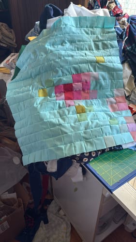 Customer's Tilda precut quilt kit in progress, showing a completed section with a colorful flower design on a light blue background.