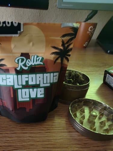 Customer's California Love THCA Flower packaging on a desk with an open grinder holding the product.
