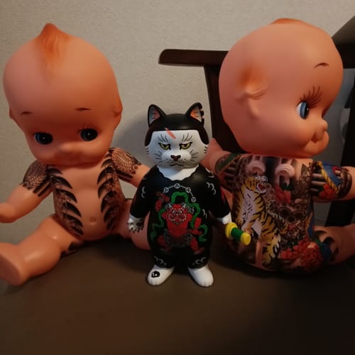 Customer's Donburi Toy figurine displayed between two large, tattooed dolls.