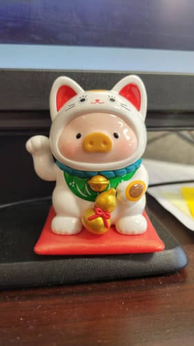 Customer's LuLu the Piggy Lucky Cat figure sitting on a red cushion with one paw raised in a wave.