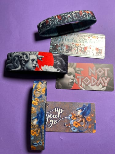 Reviewer's three artistic wristbands and matching collector cards from the Mystery Club+ laid out on a purple surface.